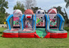 A large inflatable outdoor game bounce house set on a grassy field, featuring four sports-themed shooting lanes with baseball, basketball, soccer, and football graphics, plus blue arches and red bases.