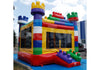A colorful inflatable bounce house front side live view designed to look like a giant building with a castle-like structure on top, featuring a vibrant red, yellow, green, and blue color scheme with a transparent front panel.