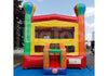 A large inflatable children's bounce house with a slide, photographed outdoors on a blue ground cover under a partly cloudy sky. The structure is primarily red and yellow with green and orange sections, and a small blue base.