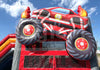 Inflatable monster truck bounce house with large wheels and colorful design against a blue sky.