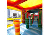 A colorful inflatable bounce house or play structure with a blue floor, red and yellow ceiling, green arches, and striped yellow, orange, and red pillars. A watermark reading Big Top Inflatables is visible across the center.