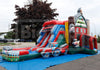 A large inflatable children's bounce house and slide set with a truck-themed section, photographed outdoors on a blue floor cover in a parking-lot setting with trees and parked cars in the background.