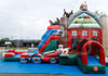 A large inflatable farm-themed bouncy castle with a red barn, blue slide, tractor, cow, and pig decorations, set up outdoors on a blue ground cover.