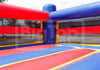 A red, blue, and yellow inflatable bouncy castle with padded corner posts and a boxing-ring style boundary, photographed outdoors with a faint 'Inflatable' watermark across the center.