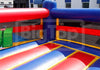 A large inflatable bounce house or play structure with red, blue, and yellow sections, photographed outdoors in front of a building. 