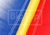 Close-up of a fabric surface with three diagonal color panels: blue on the left, yellow in the center, and red on the right, separated by white stitched lines. 