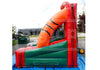 An inflatable bounce house with a basketball-themed slide, featuring red, green, and orange sections, set up outdoors on a blue tarp with a building and trees in the background.