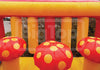 Inflatable bouncer with red and yellow mushroom decorations against a blurred outdoor background.