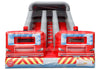 An inflatable fire station themed bouncy castle with a central slide, featuring red fire truck fronts, blue sky graphics, and yellow and red hazard stripes on the base.