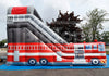 An inflatable fire truck themed slide and bounce house set up outdoors on a blue ground cover, with trees and a cloudy sky in the background.